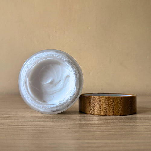 Jar of white cream with wooden lid on a beige background