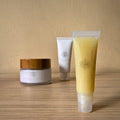 Three skincare products on a wooden surface with a beige background