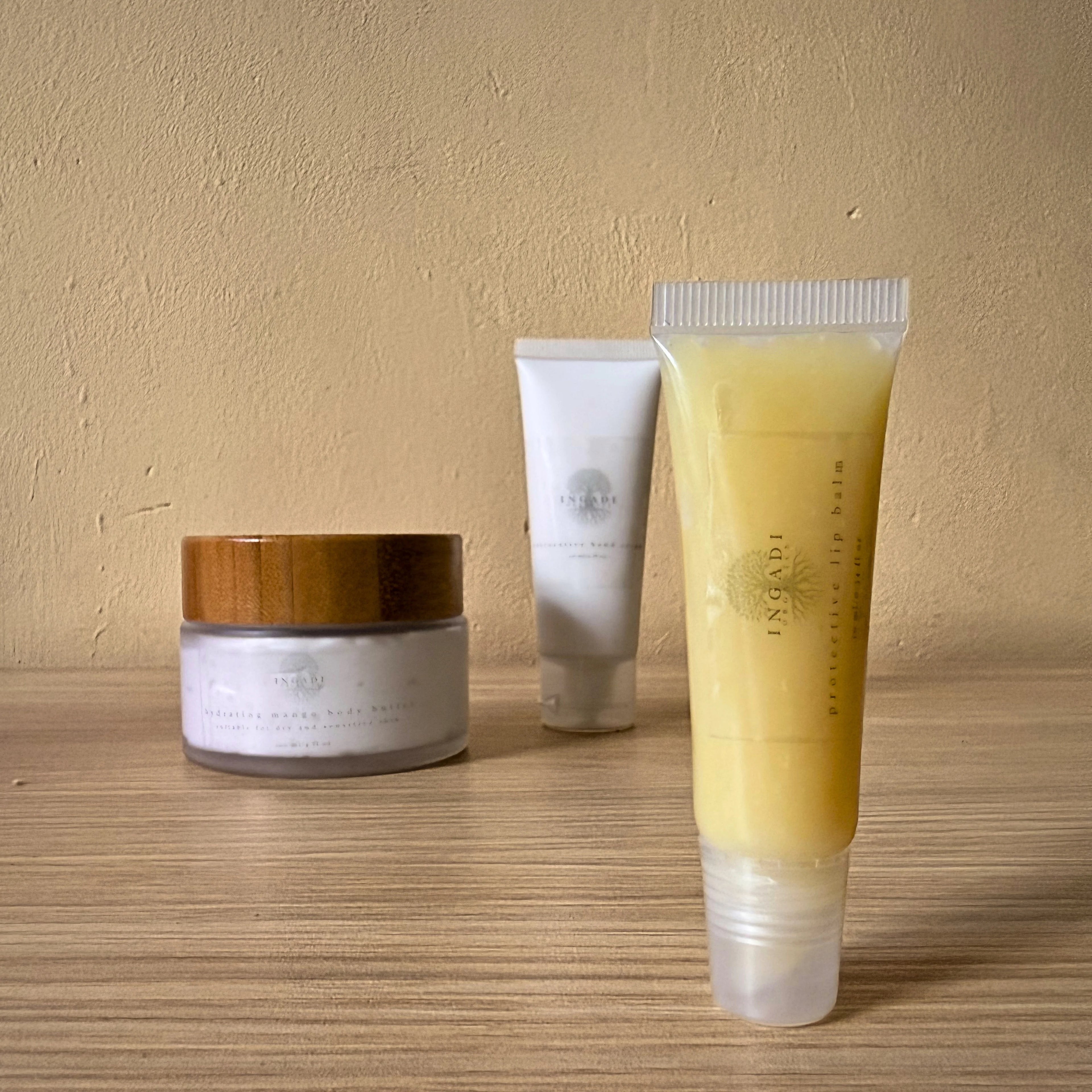 Three skincare products on a wooden surface with a beige background