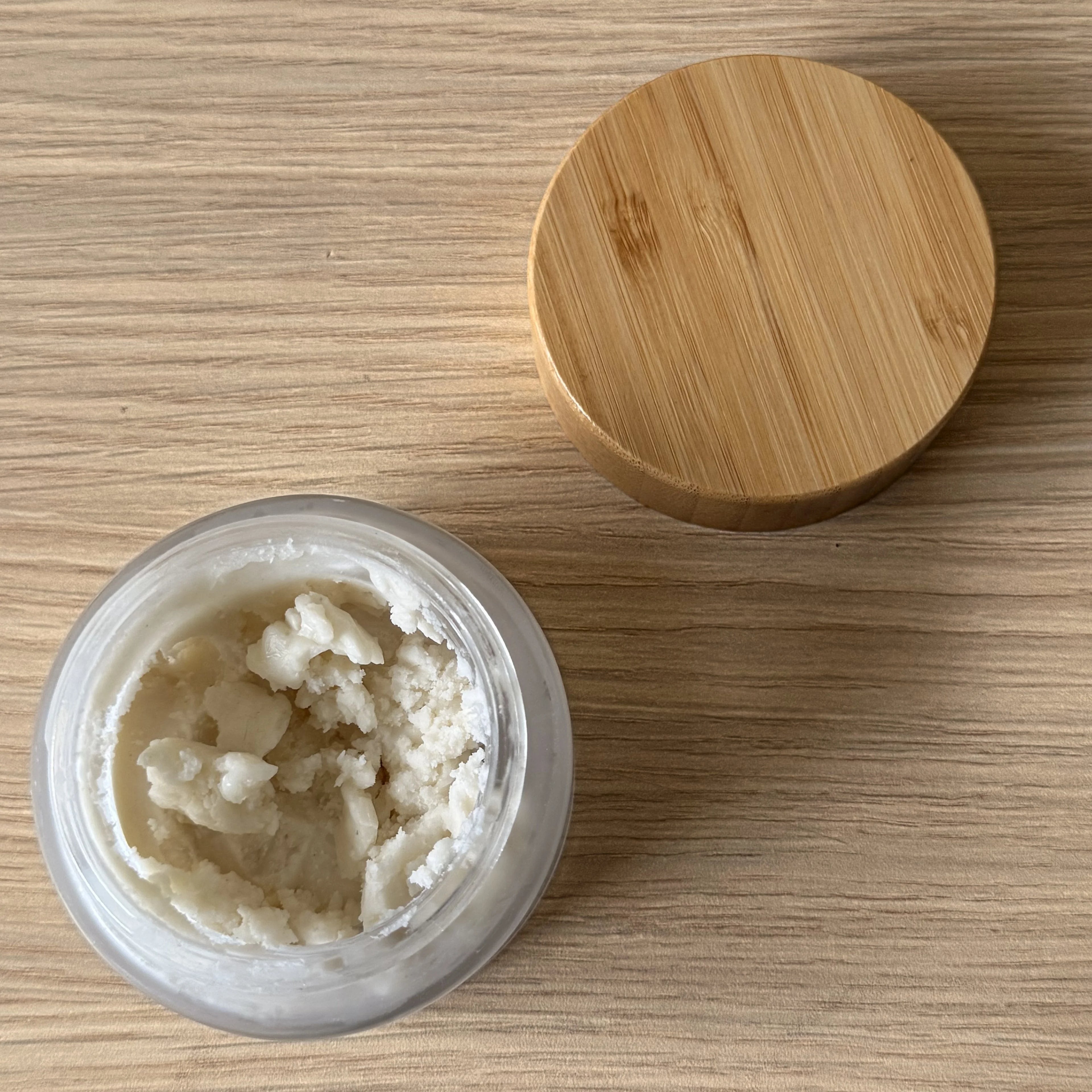 Jar of cream with a wooden lid on a wooden surface